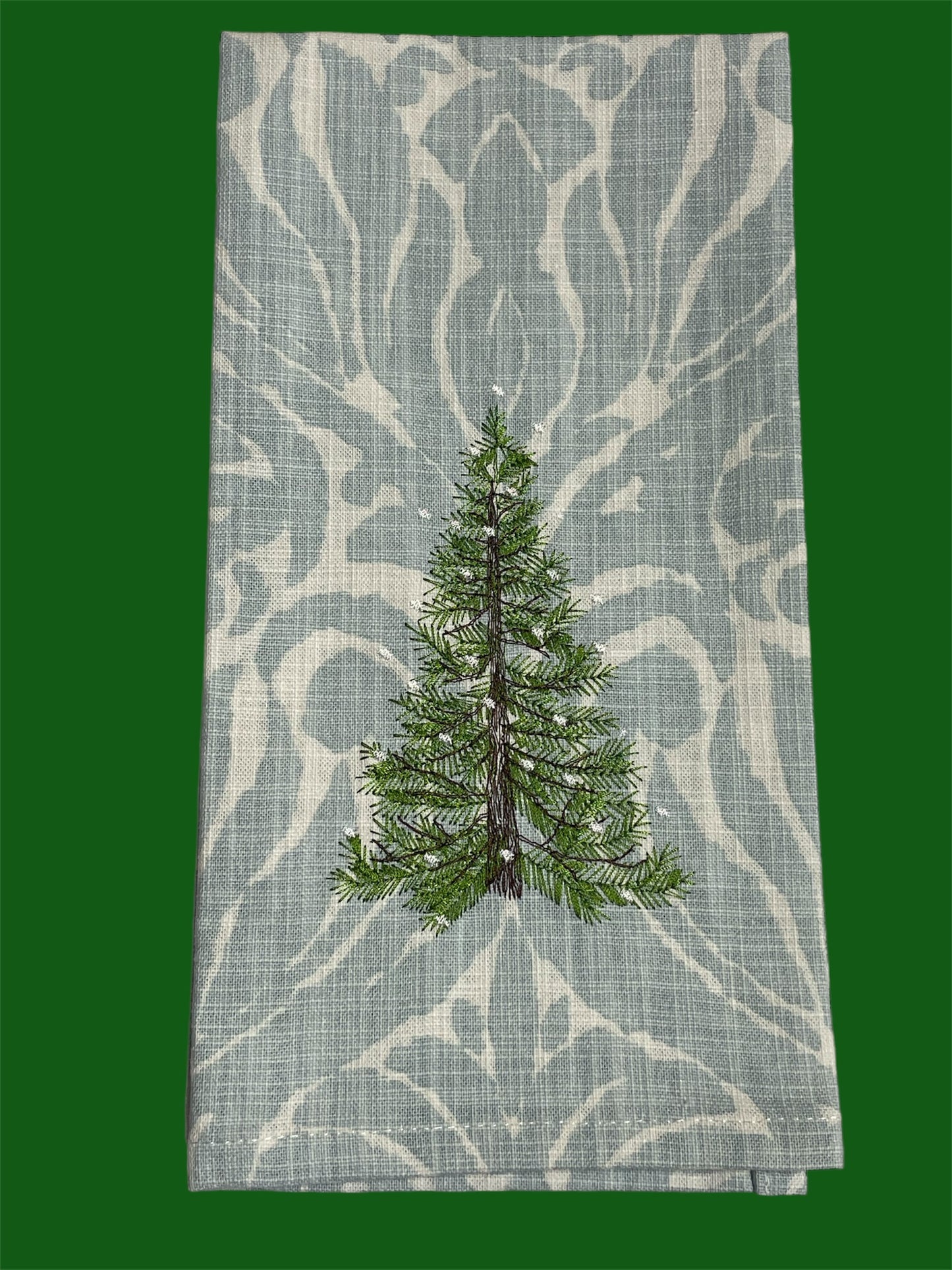 Decorative hand towel featuring embroidered Christmas pine tree on elegant patterned background, perfect for holiday and winter seasonal decor.