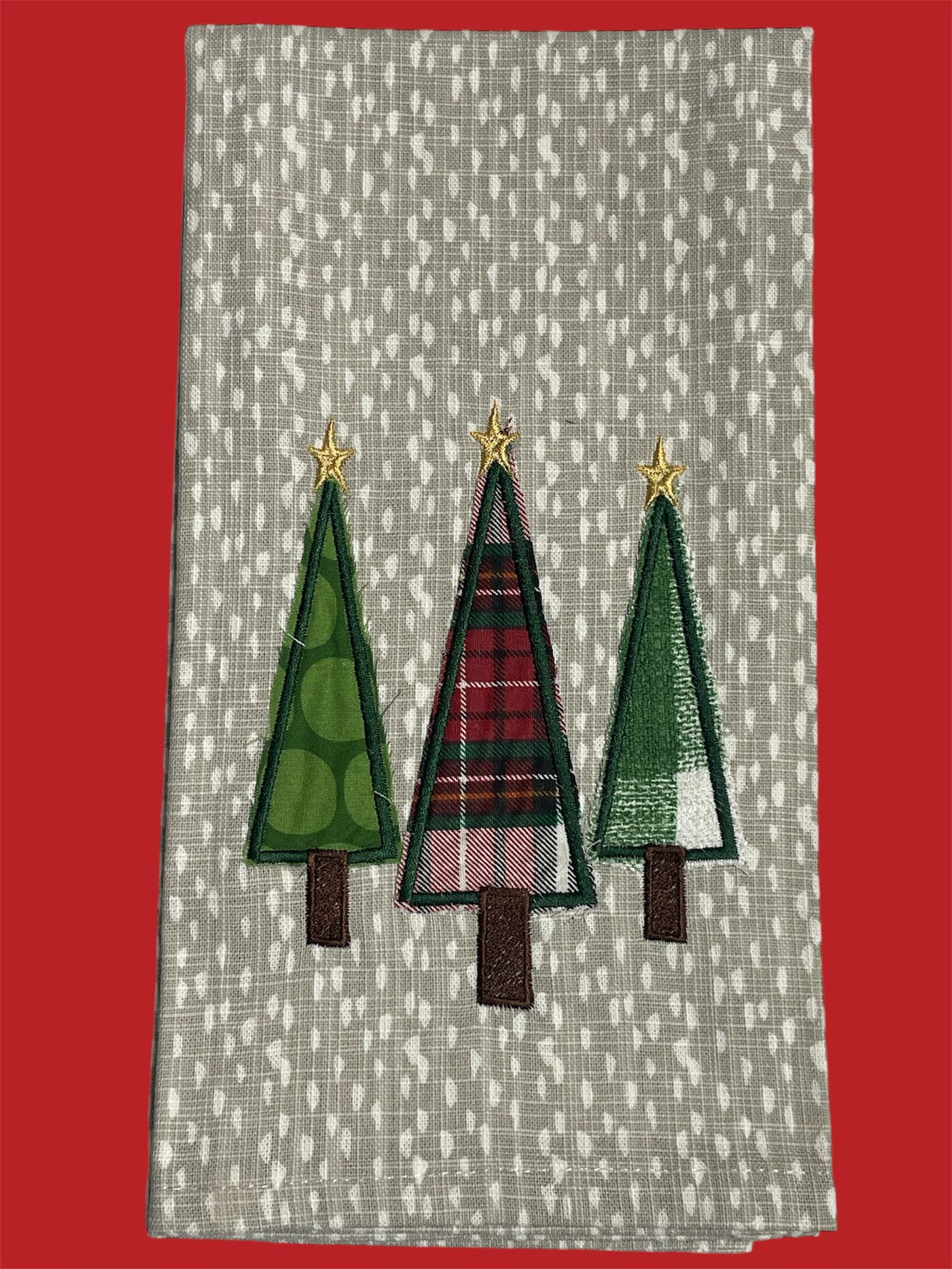 Christmas kitchen towel with three embroidered Christmas trees in green and plaid patterns, each topped with a gold star, perfect for holiday kitchen decor.