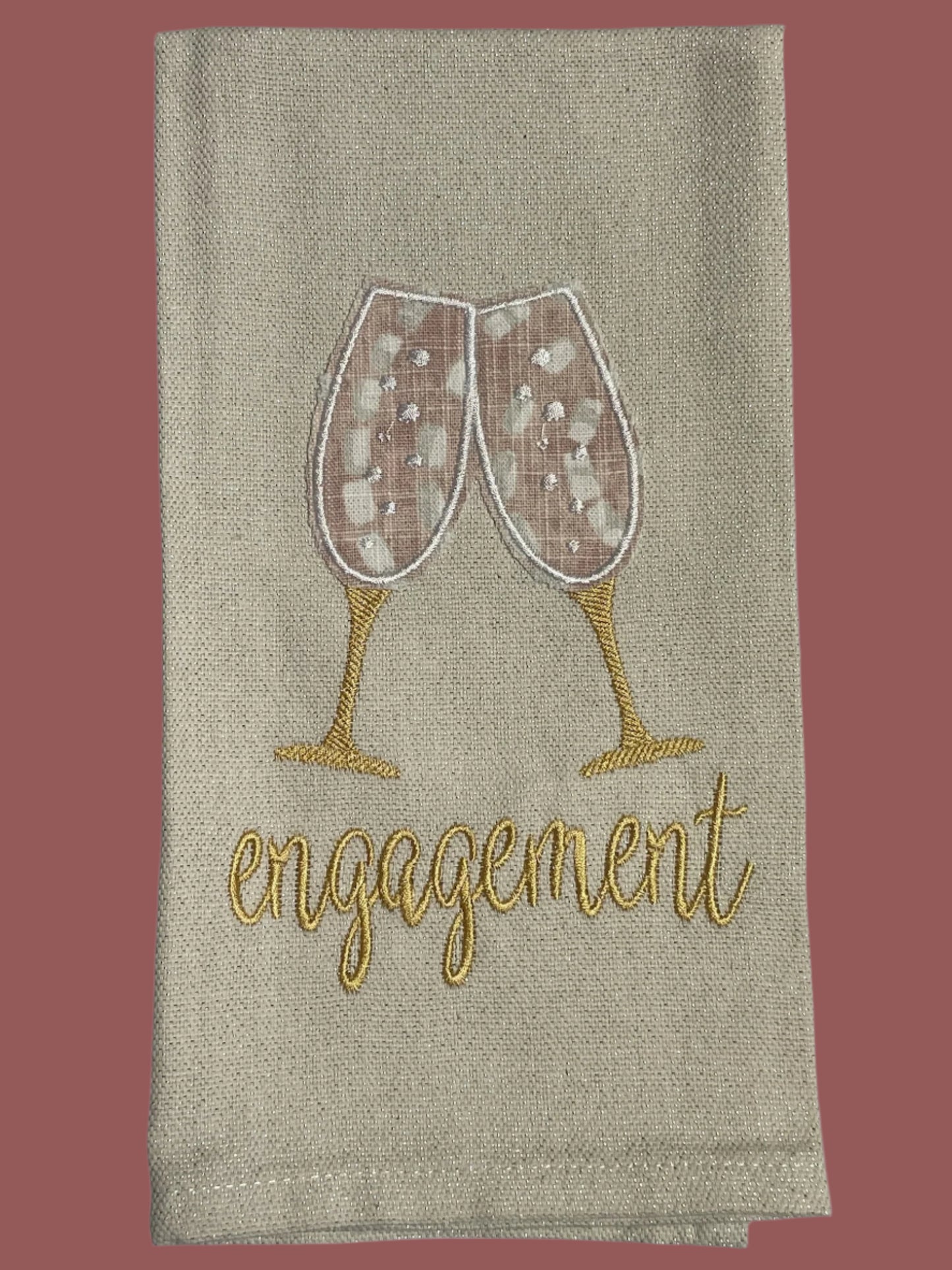 Decorative hand towel with embroidered champagne glasses and engagement text, perfect for engagement parties, bridal showers, and wedding gifts.