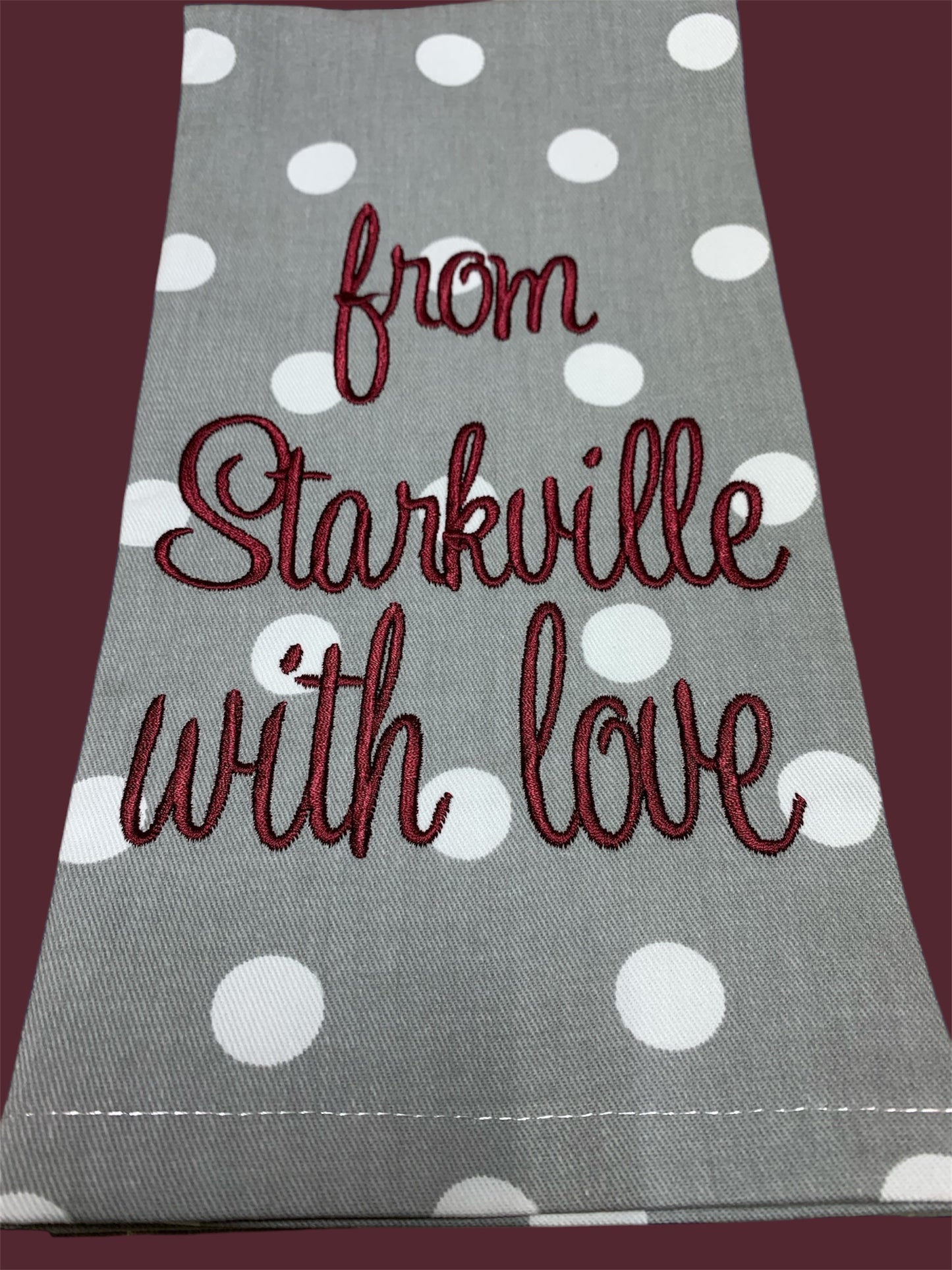 Decorative hand towel featuring embroidered "from Starkville with love" text in maroon on gray polka dot fabric, perfect for Mississippi State fans, kitchens, or game day decor.
