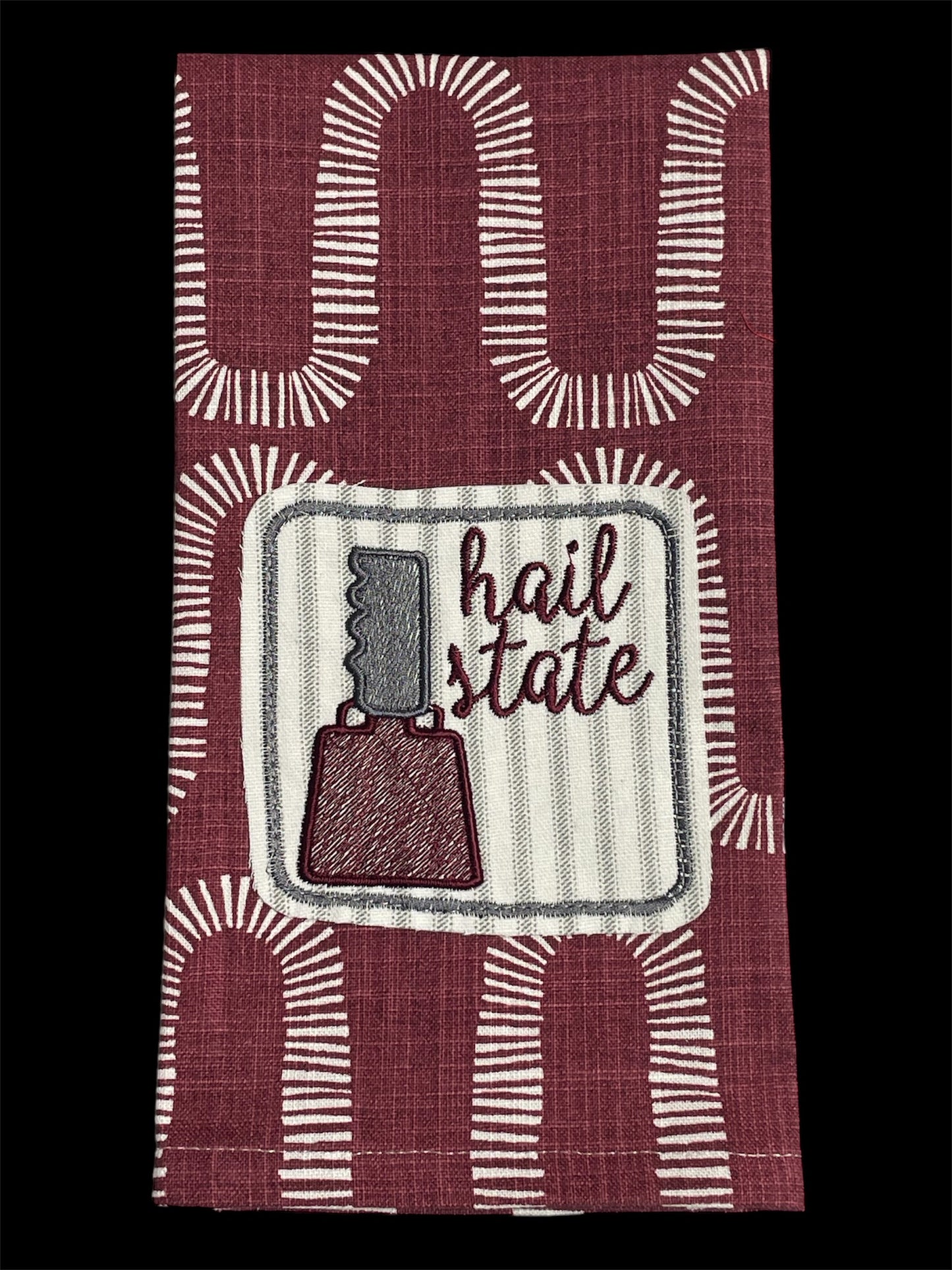 Decorative hand towel featuring embroidered Mississippi State cowbell and “Hail State” text on maroon patterned background, perfect for MSU fans and game day decor.