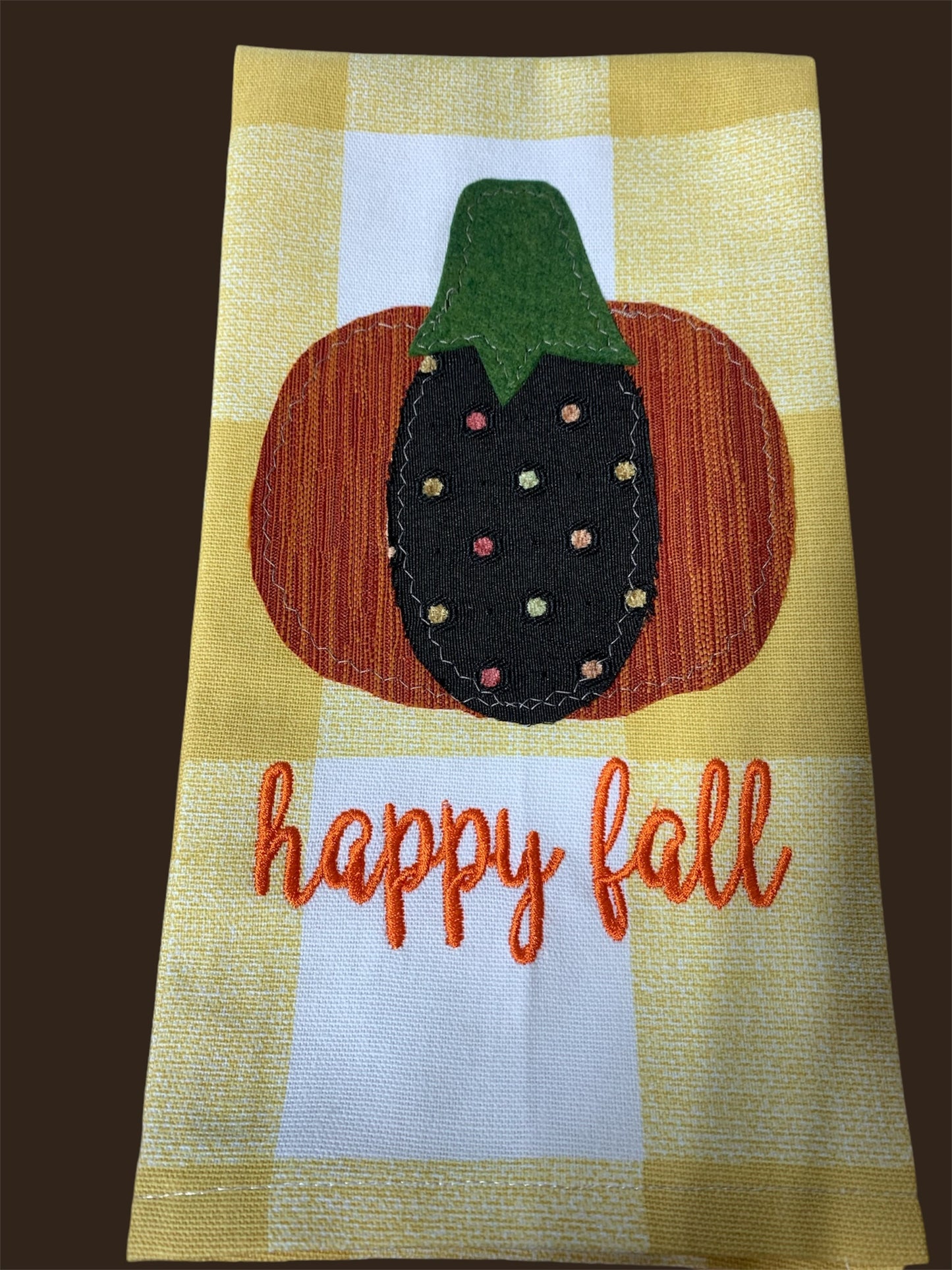 Decorative hand towel featuring embroidered pumpkin with colorful polka dots and “Happy Fall” text on yellow checkered background, perfect for autumn and seasonal kitchen decor.