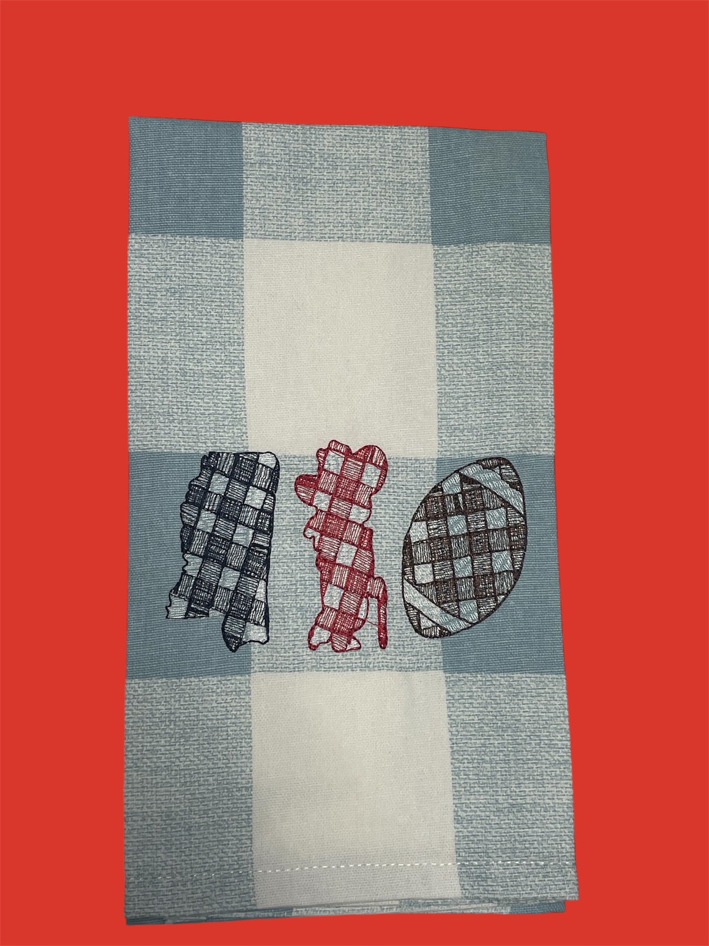 Embroidered hand towel featuring plaid designs of the state of Mississippi, a dog silhouette, and a football on a light blue and white checkered background, perfect for Ole Miss football fans and Southern decor.