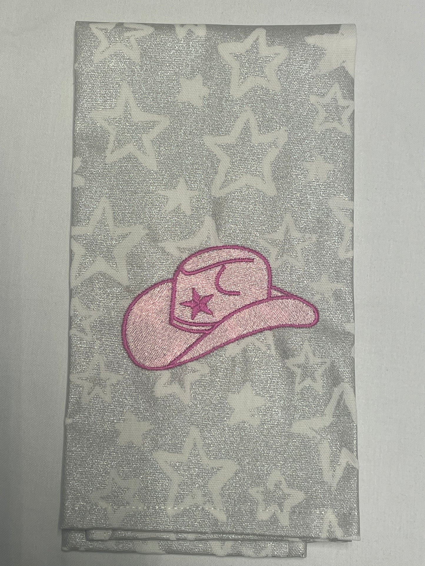 Decorative hand towel featuring embroidered pink cowgirl hat with star and moon detail on silver star-patterned background, perfect for western-themed kitchen decor and gifts.