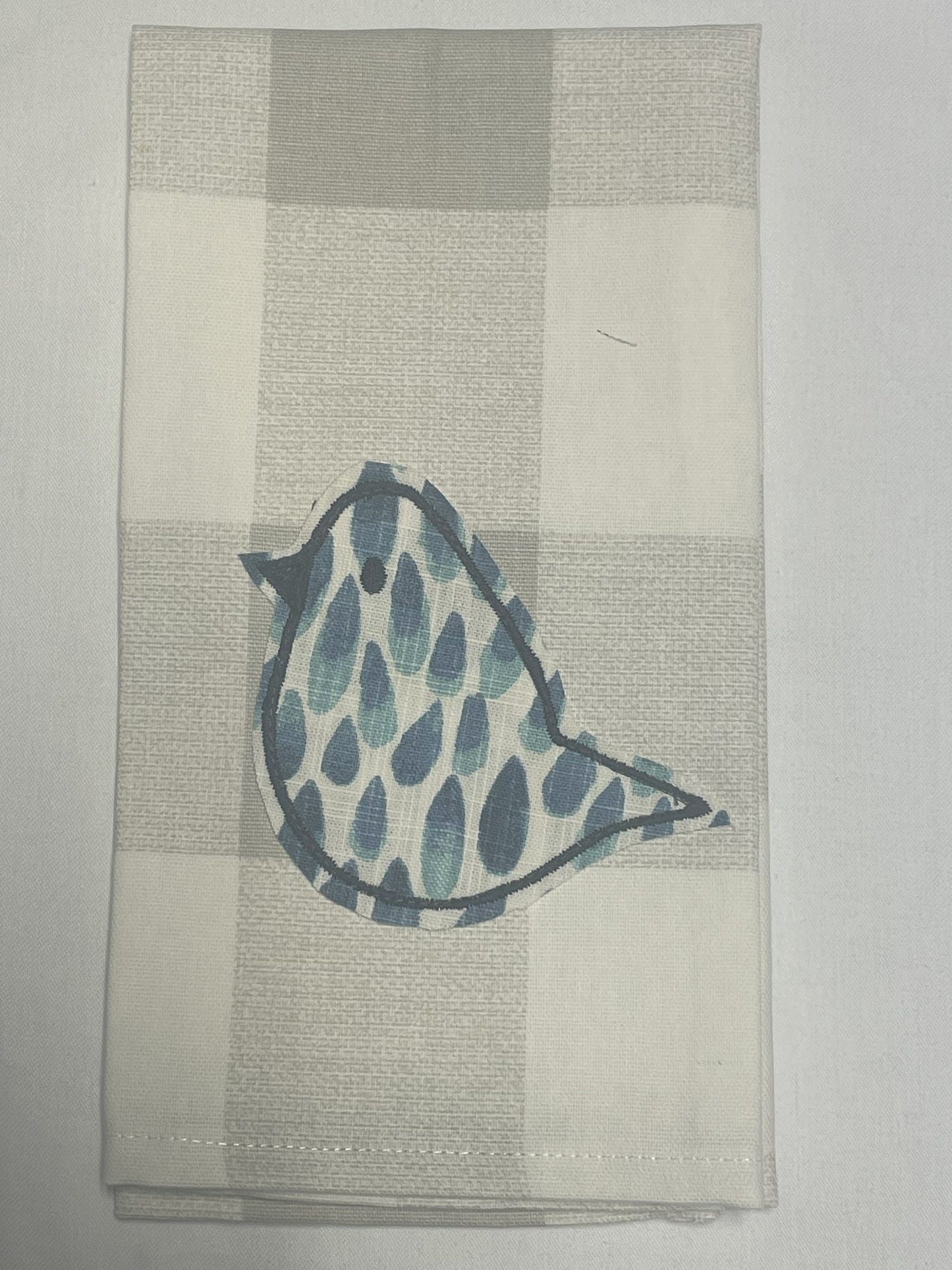 Decorative hand towel featuring embroidered single bird with blue pattern on neutral plaid background, perfect for farmhouse, spring, and everyday kitchen decor.
