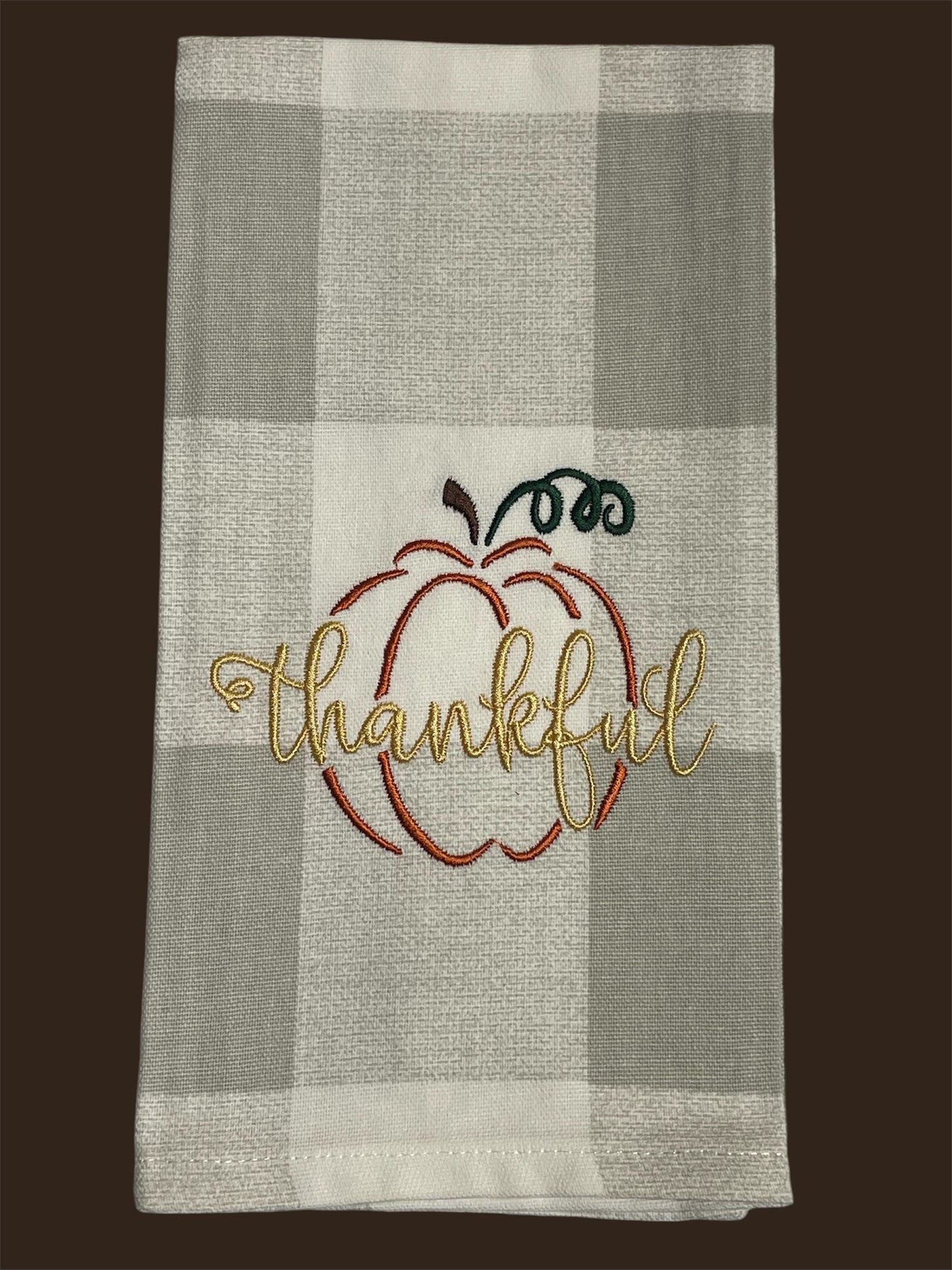Fall kitchen towel featuring an embroidered pumpkin outline with the word "thankful" stitched in gold, perfect for Thanksgiving and autumn decor.