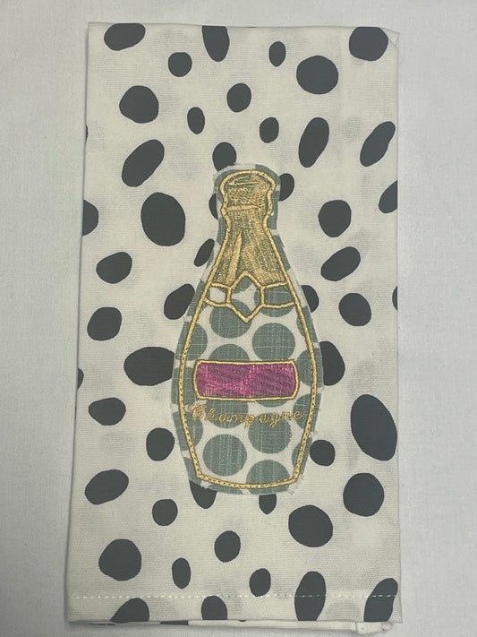 Decorative hand towel featuring embroidered champagne bottle with gold detailing and pink label on black polka dot background, perfect for celebrations, parties, and kitchen or bar decor.