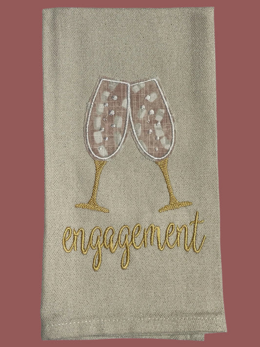 Decorative hand towel with embroidered champagne glasses and engagement text, perfect for engagement parties, bridal showers, and wedding gifts.