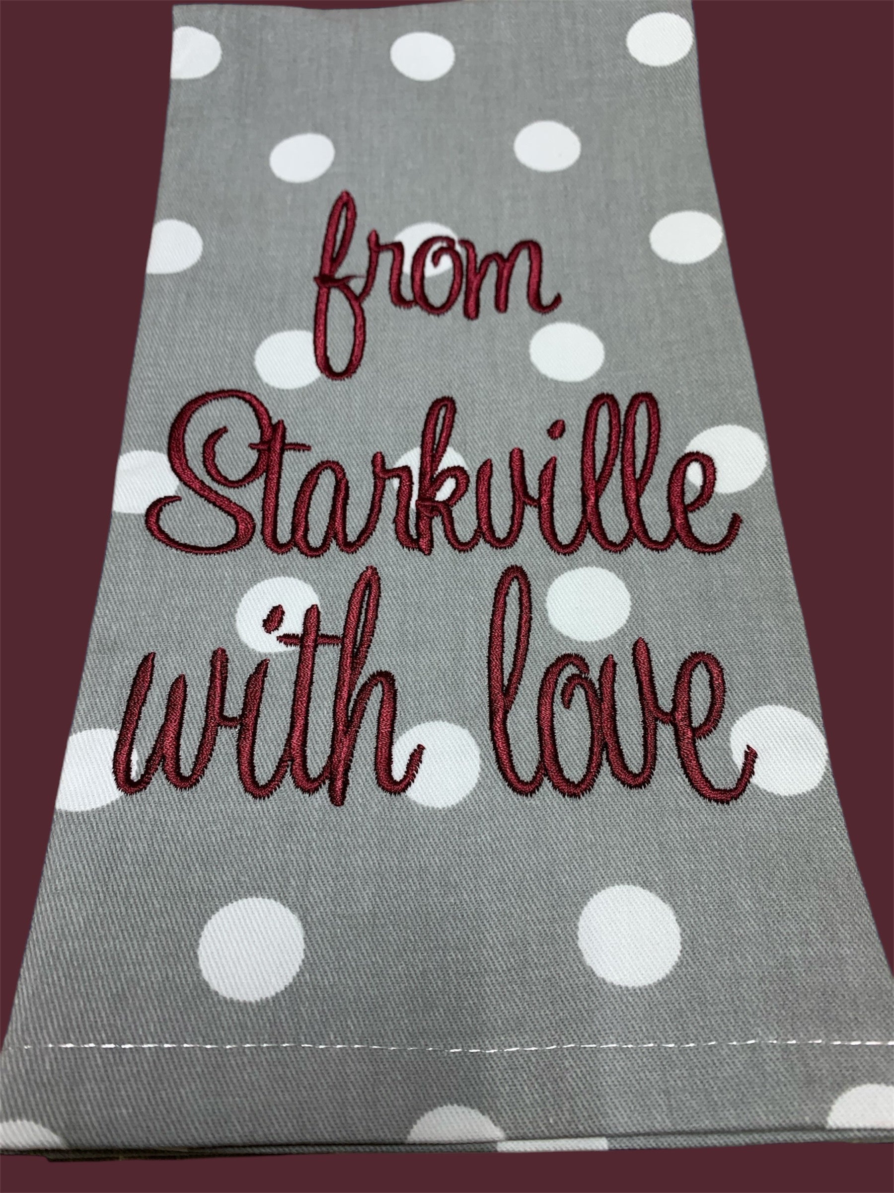 Decorative hand towel featuring embroidered "from Starkville with love" text in maroon on gray polka dot fabric, perfect for Mississippi State fans, kitchens, or game day decor.