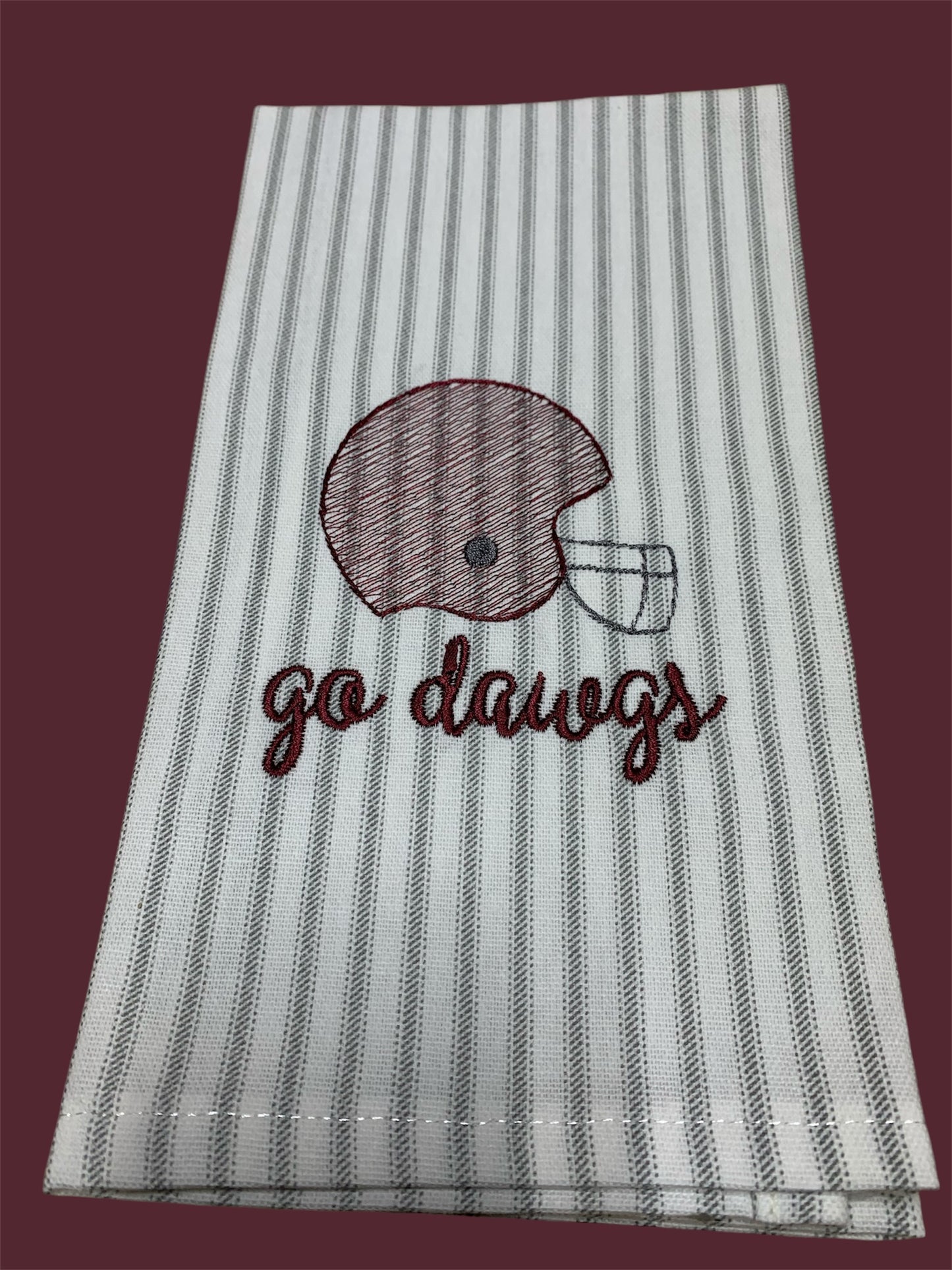 Hand towel with embroidered maroon football helmet and "go dawgs" text on gray and white striped background, perfect for Mississippi State Bulldogs fans and gameday decorations.