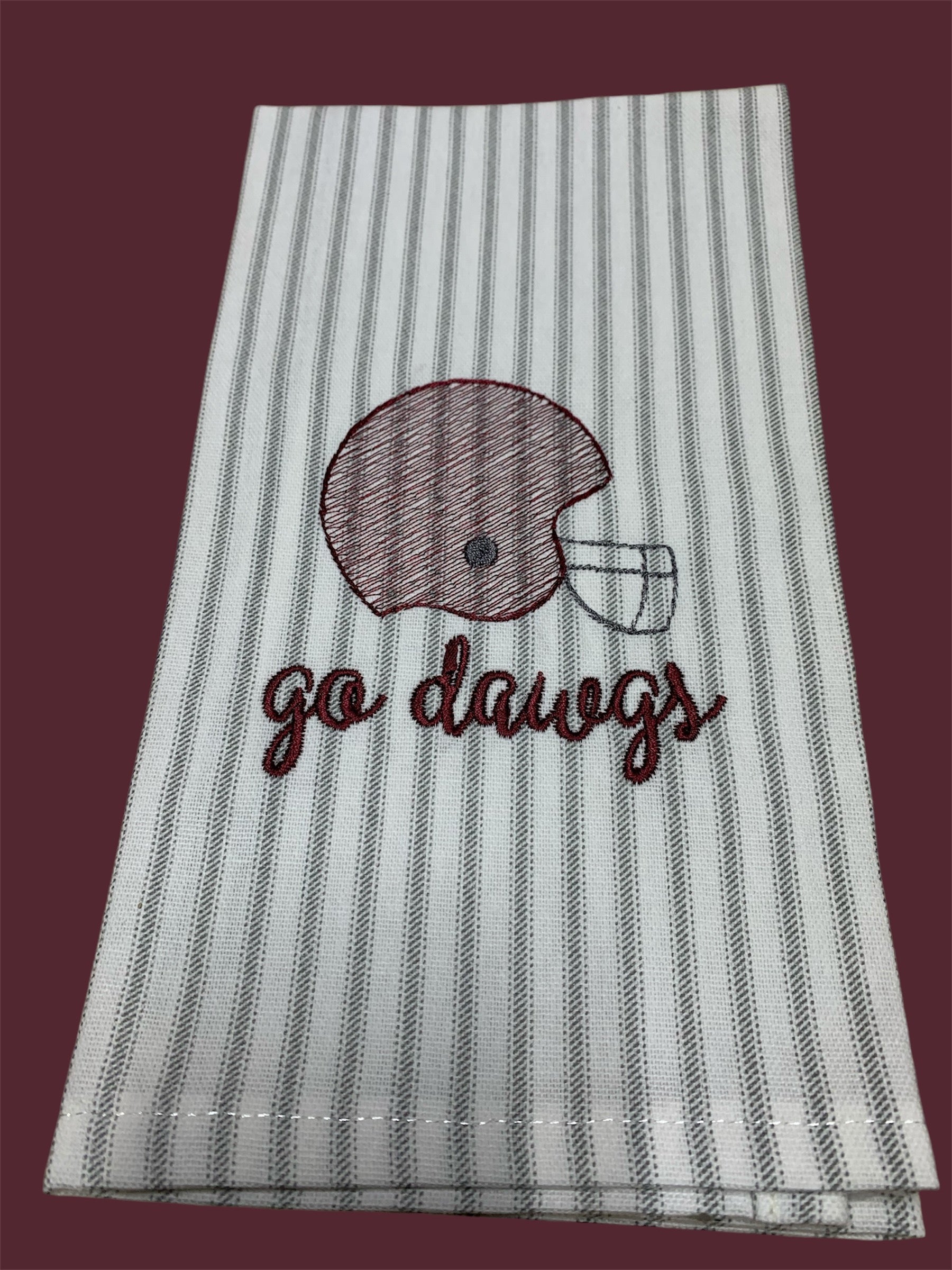 Hand towel with embroidered maroon football helmet and "go dawgs" text on gray and white striped background, perfect for Mississippi State Bulldogs fans and gameday decorations.
