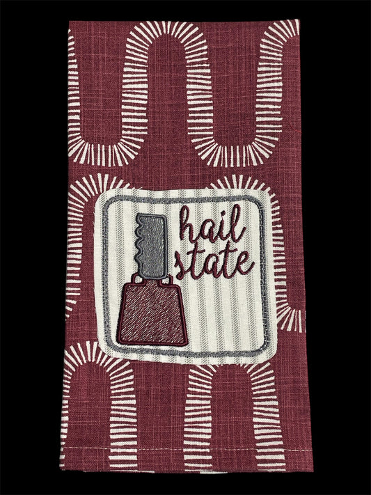 Decorative hand towel featuring embroidered Mississippi State cowbell and “Hail State” text on maroon patterned background, perfect for MSU fans and game day decor.