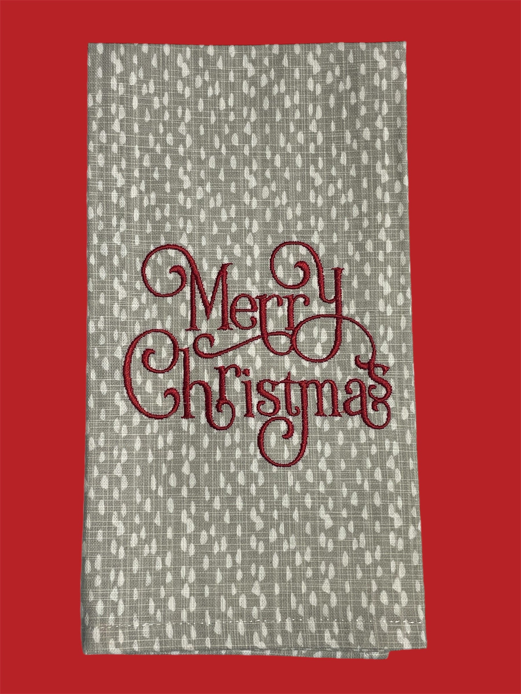 Decorative hand towel featuring embroidered “Merry Christmas” text in elegant red script on neutral patterned background, perfect for holiday and seasonal decor.