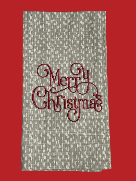 Decorative hand towel featuring embroidered “Merry Christmas” text in elegant red script on neutral patterned background, perfect for holiday and seasonal decor.