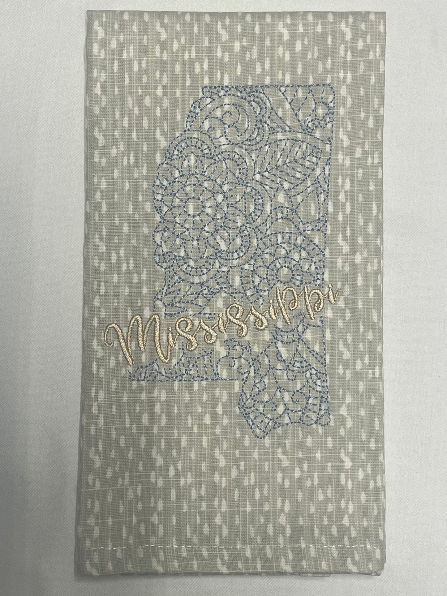 Decorative hand towel featuring embroidered Mississippi state outline with lace pattern and “Mississippi” script text, perfect for southern home decor and state pride gifts.