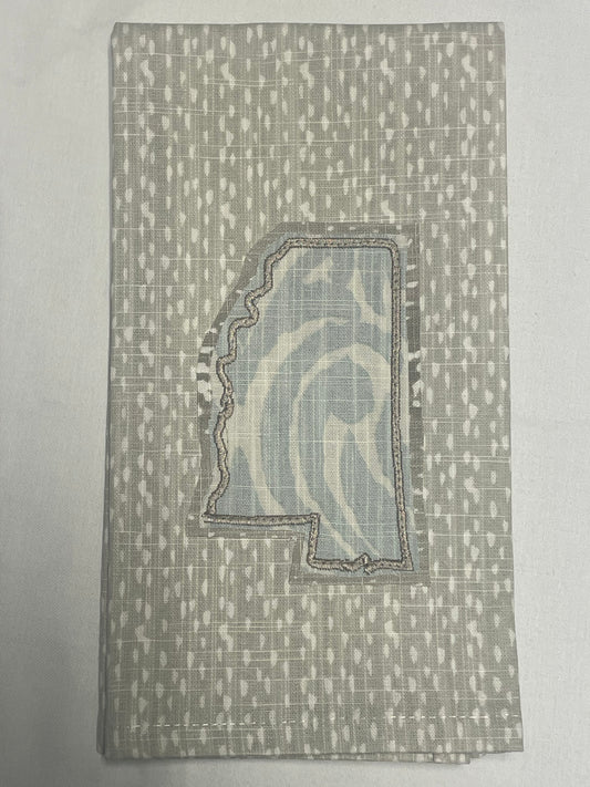 Decorative hand towel featuring embroidered Mississippi state outline with light blue abstract patterned fabric on neutral background, perfect for southern home decor and state pride gifts.