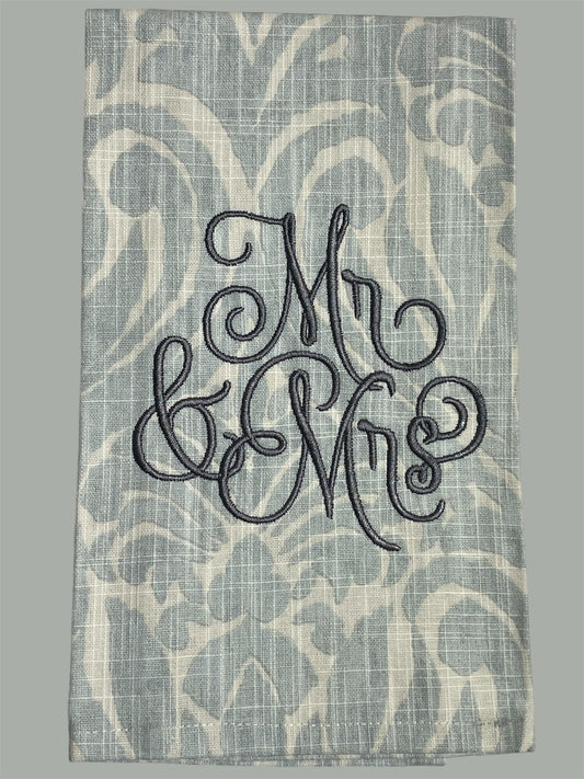 Decorative hand towel with embroidered “Mr & Mrs” text on elegant patterned background, perfect for weddings, anniversaries, or newlywed gifts.