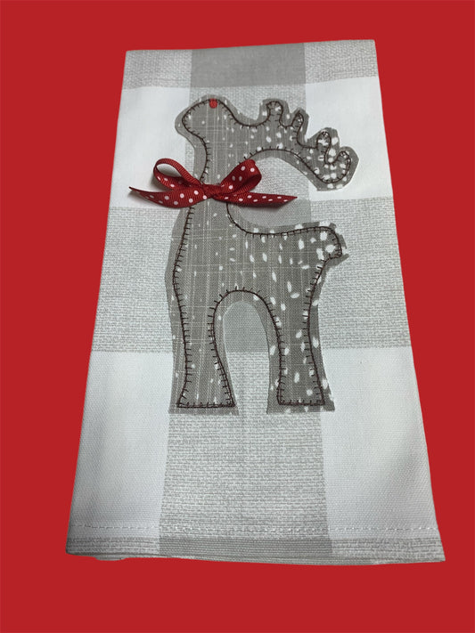 Decorative hand towel featuring embroidered reindeer silhouette with red polka dot bow and small red accent on antler, displayed on neutral plaid background, perfect for Christmas holiday decor.