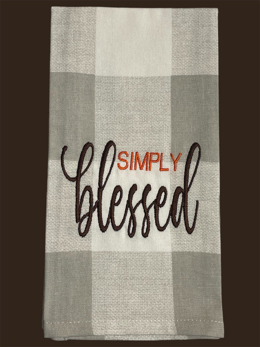 Decorative hand towel featuring embroidered "Simply Blessed" text in orange and brown on a neutral gray and white buffalo check background, perfect for year-round kitchen or home decor.