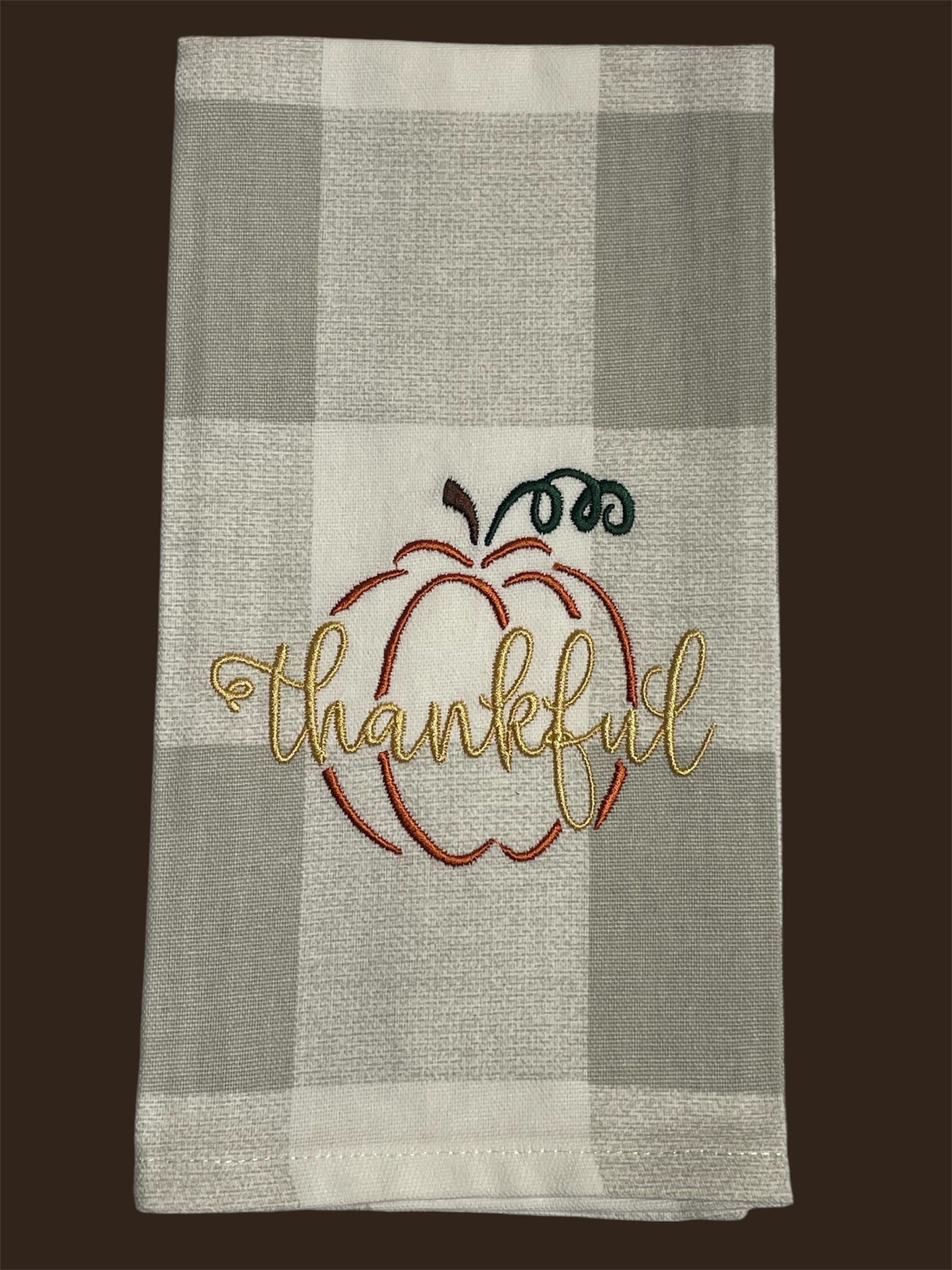 Fall kitchen towel featuring an embroidered pumpkin outline with the word "thankful" stitched in gold, perfect for Thanksgiving and autumn decor.