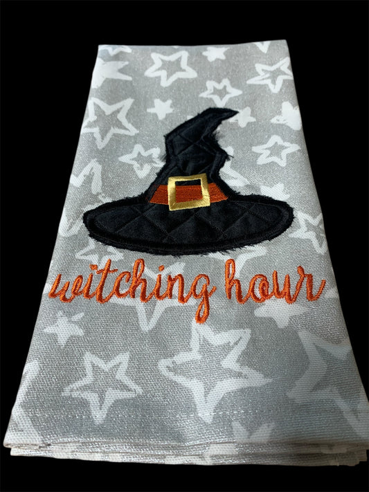 Decorative hand towel with embroidered witch hat and “Witching Hour” text on star-patterned background, perfect for Halloween and spooky seasonal decor.